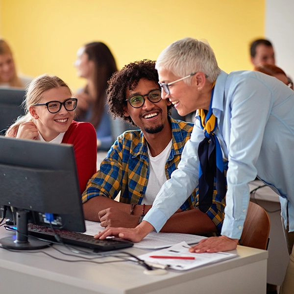 A photo of two students working on a computer with a professor