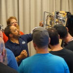 A group of technicians looking at the inside of a pinball machine