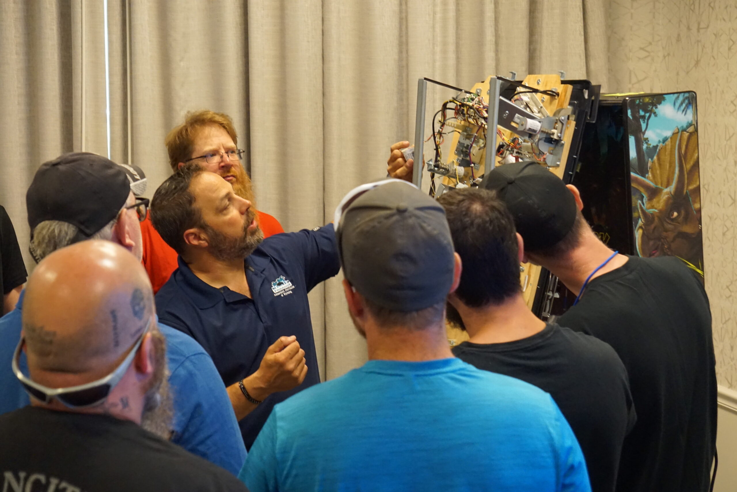 A group of technicians looking at the inside of a pinball machine
